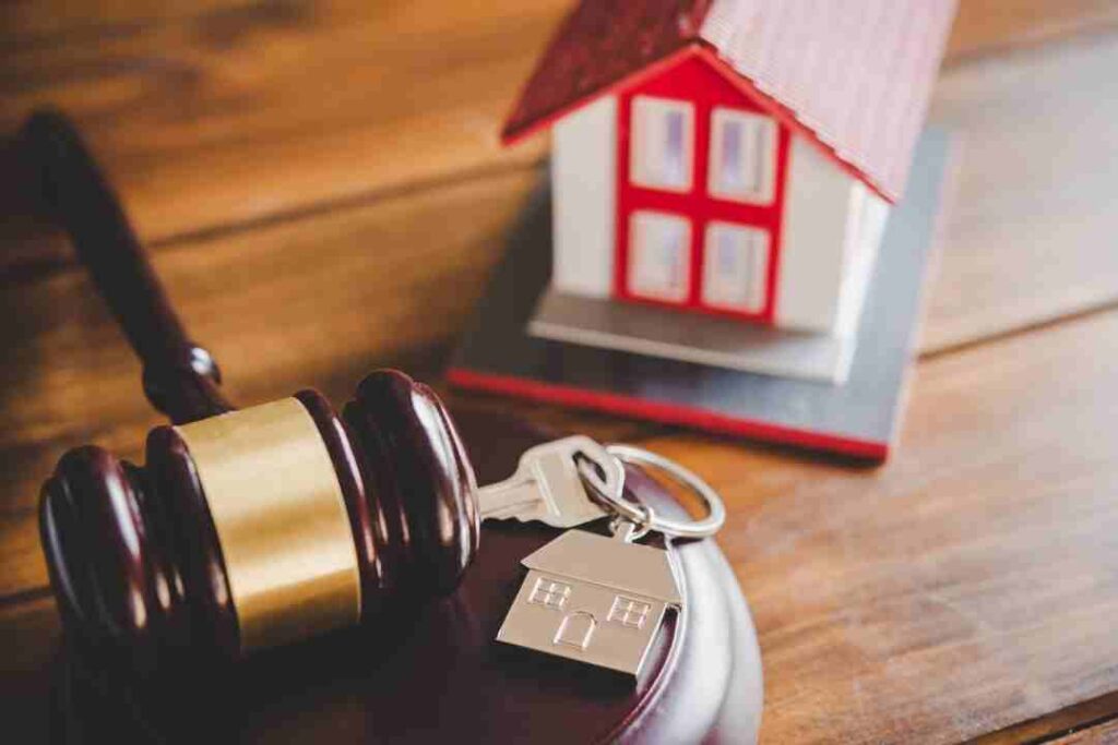 Gavel, house keys, and a model house for real estate law.